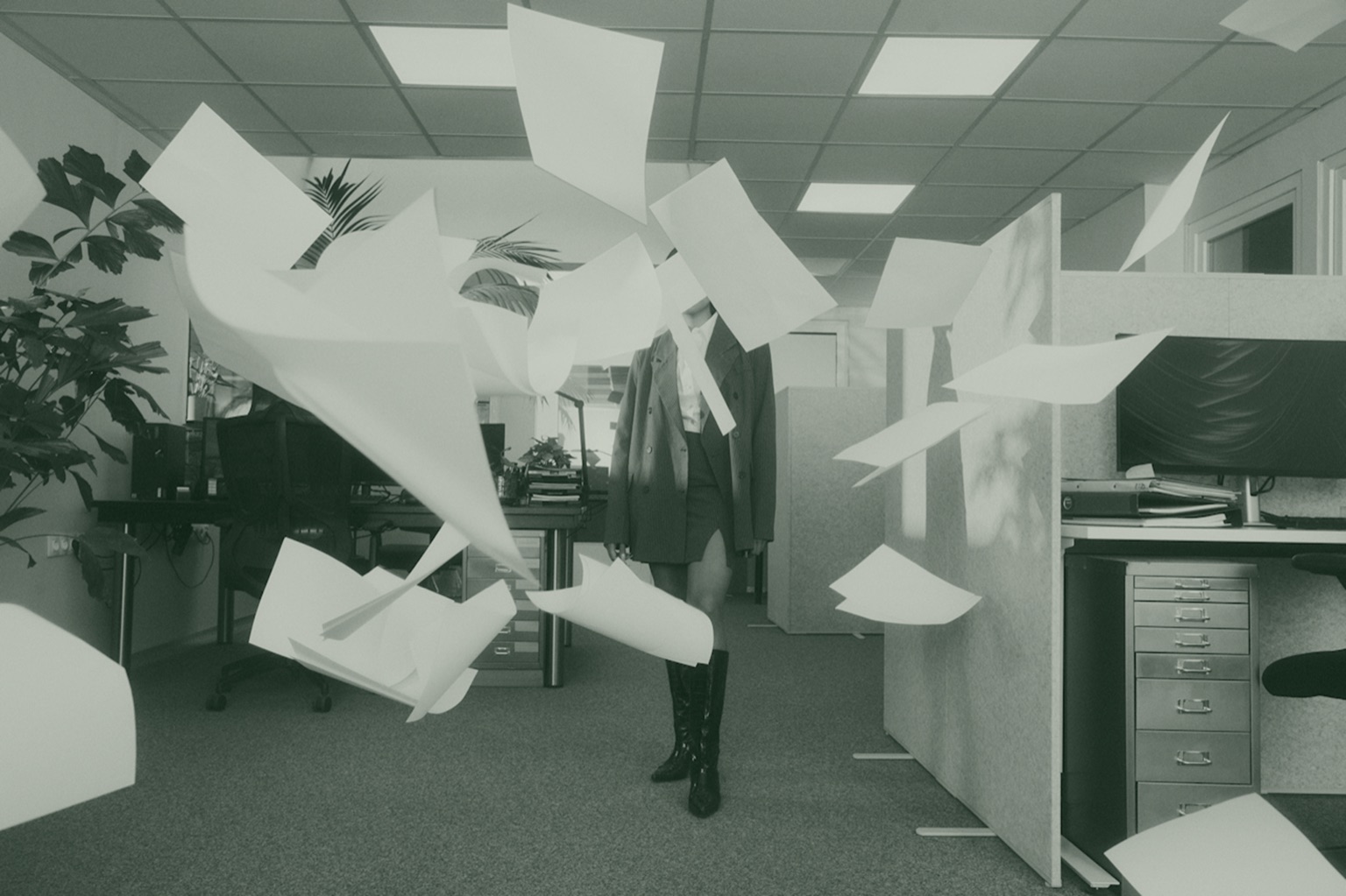 Papers flying through the air in an empty office cubicle