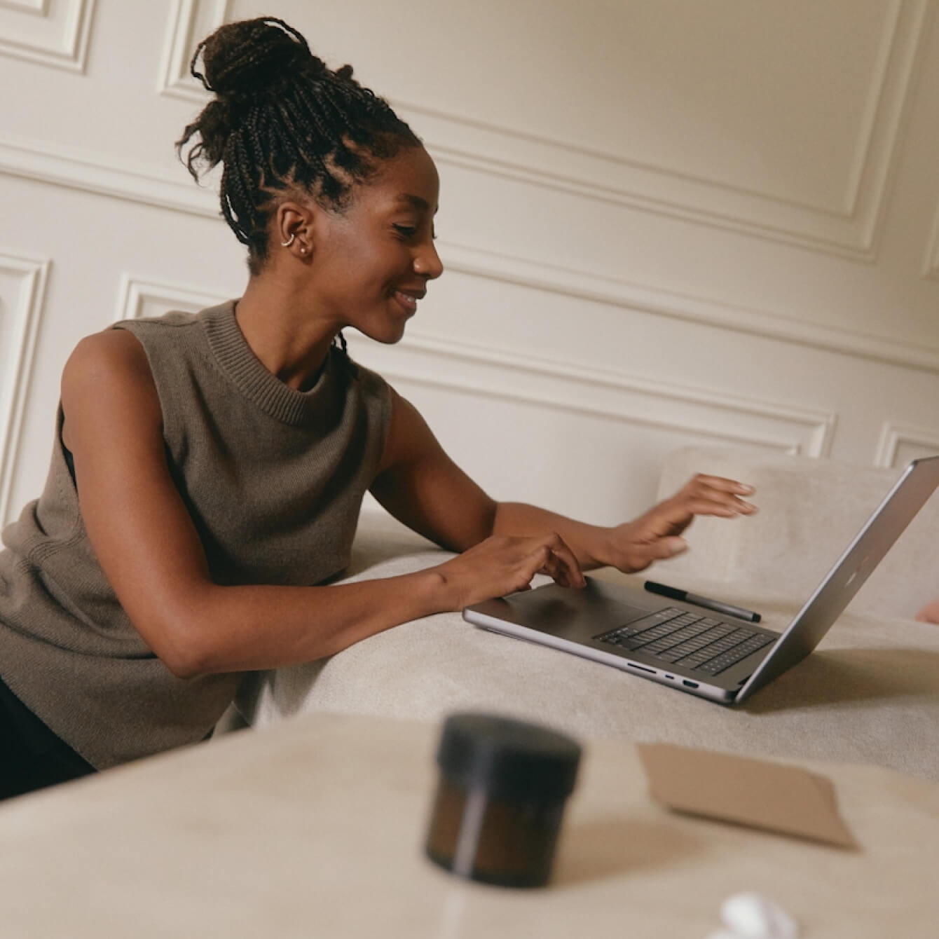 A woman smiling while working on a laptop at a table